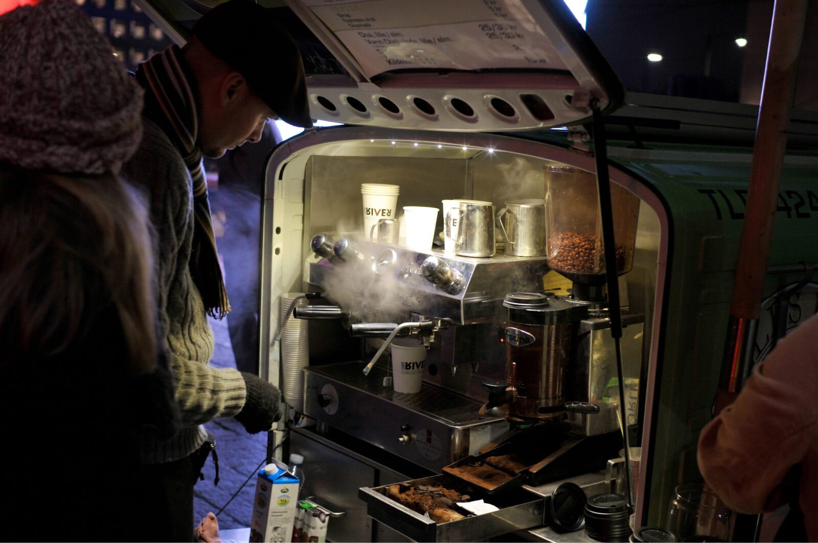 A man makes coffee on a street cart on a cold night